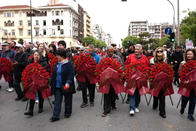 Μέλη σωματείων κρατώντας στεφάνια, συμμετέχουν σε πορεία προς το μνημείο Πεσόντων Εργατών, μπροστά από τον σταθμό «Βενιζέλου» του Μετρό Θεσσαλονίκης